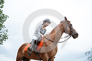 Female equestrian smiling while riding horse and holding reins photo
