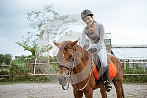 Female equestrian smiling while riding horse and holding reins photo