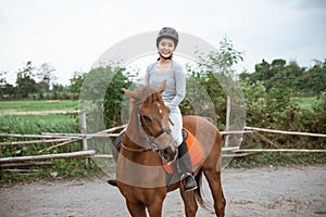 Female equestrian smiling while riding horse and holding reins photo