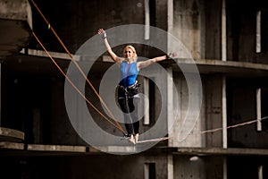 Female equilibrist balancing with arms raised on the slackline rope