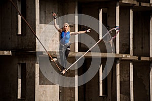Female equilibrist balancing with one arm raised and other to the right on the slackline