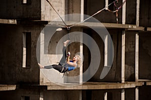 Female equilibrist hanging on the slackline upside down