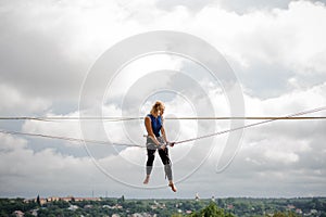 Female equilibrist sitting on the slackline rope