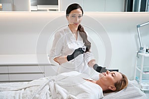 Female esthetician stands with syringe in her hand near patient