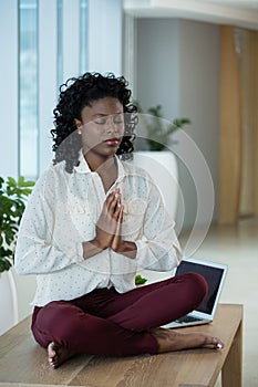 Female executive meditating on desk