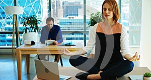 Female executive meditating at her desk