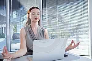 Female executive performing yoga at desk