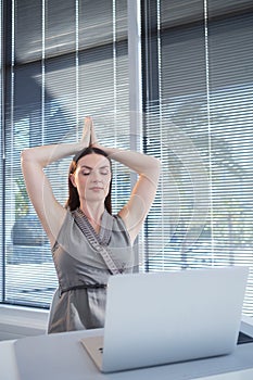 Female executive performing yoga at desk