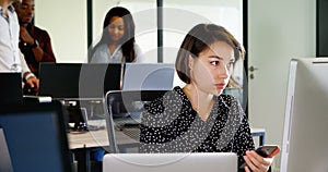 Female executive using mobile phone at desk 4k