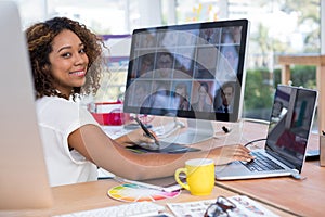 Female executive working over graphic tablet at her desk in office