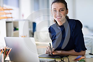Female executive working over laptop and graphic tablet at her desk