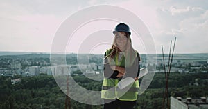 Female expert engineer on the top of building looking at camera smiling and turned around with back looking to the