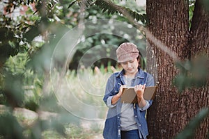 The female explorers leaned against a tree to relieve fatigue and were taking notes from the journey