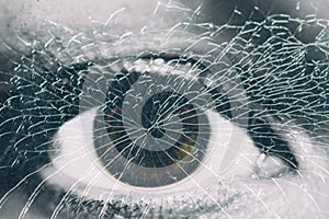 A female eye behind the broken glass