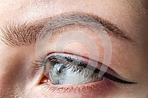 Female eye of blue color of a young girl close-up. Eye and eyebrow makeup.Permanent makeup for eyelids and eyebrows