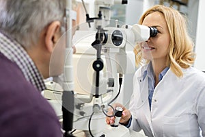 Female eye doctor looks at patient eyes using apparatus