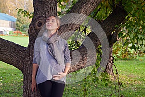 Female face, closed eyes close-up, A pregnant woman standing alone in the park, melancholy eyes closed.