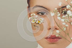 Female face with flowers and Hope inscription, close up portrait