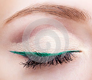 Female face makeup with closed eye and green eyeliner