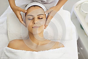 Female face massage in a beauty salon. Beautician makes facial skin treatment in a beauty clinic