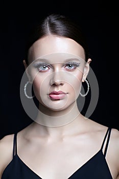 Female face with unusual rhinestones makeup. Woman with earring in the form of a shiny ring in the ear