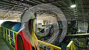 Female factory worker in protective gear checking out city trash dump indoors