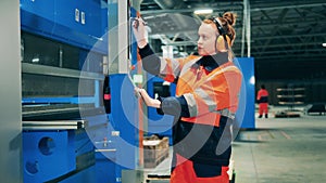 Female factory worker uses her stylus to operate a machine through touchscreen