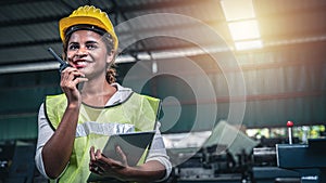 Female factory worker using handheld radio receiver for communication.