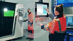 Female factory worker using stylus to operate a machine