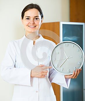 Female family doctor with big clock.