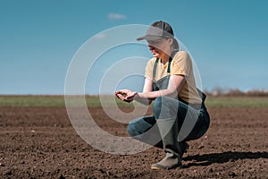 Female farmer agronomist checking the quality of ploughed field soil before sowing season