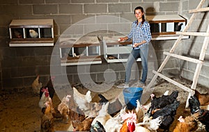 Female farmer collecting eggs in henhouse