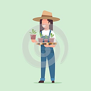 Female farmer holding potted plants woman in uniform planting young seedlings in garden agricultural worker eco farming