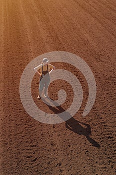 Female farmer looking over ploughed field, drone photography