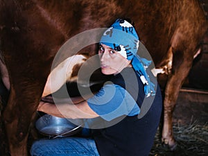 Female farmer milking a homemade cow in a barn