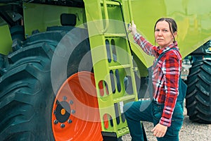 Female farmer posing in front of combine harvester