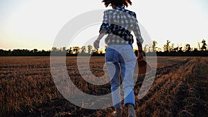 Female farmer running through the barley plantation at sunset. Agronomist jogging among wheat meadow at dusk. Beautiful