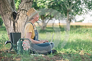 Female farmer using laptop computer in walnut orchard, innovative technology in organic farming