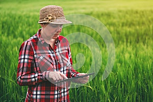 Female farmer using tablet computer in wheat crop field