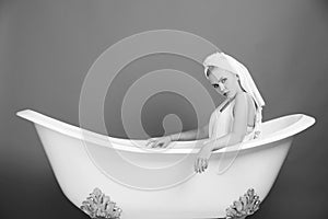 Female fashion concept. pretty woman with towel turban sitting in white bathtub