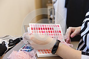 Female fashion designer holding color samples choosing fabric textile at workplace