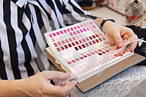 Female fashion designer holding color samples choosing fabric textile at workplace