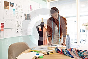 Female fashion designer looking at sketches on table in a modern office