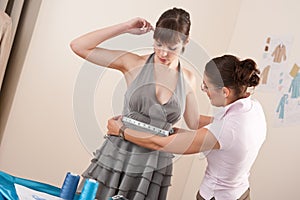 Female fashion designer measuring model