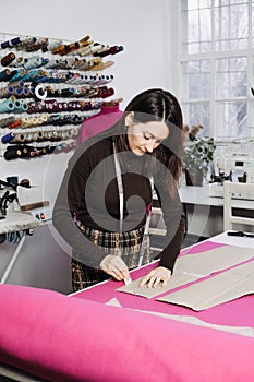 Female fashion designer tailor making sewing patterns at workplace in sewing studio.