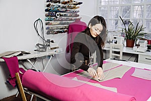 Female fashion designer tailor making sewing patterns at workplace in sewing studio. Seamstress working