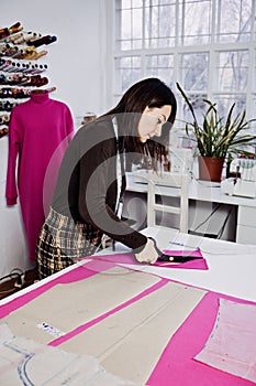 Female fashion designer tailor making sewing patterns at workplace in sewing studio. Seamstress working