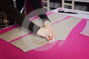 Female fashion designer tailor making sewing patterns at workplace in sewing studio. Seamstress working