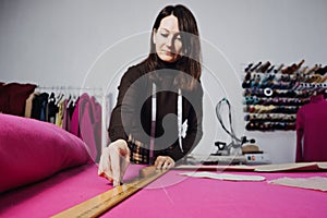 Female fashion designer tailor making sewing patterns at workplace in sewing studio. Seamstress working