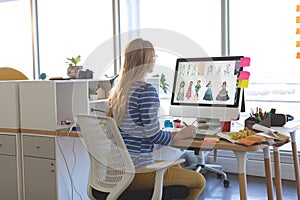 Female fashion designer using graphic tablet while working at desk